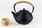 Closeup of black teapot with rope on handle and a skein of rope on white background