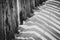 Closeup black and white shot of beach details with a fence along the dune line on a coast