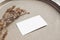 Closeup of blank business card mockup. Dry grass on beige ceramics plate. Fall and Thanksgiving concept. Autumn styled