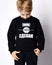 Closeup of blond kid boy in black jersey sweater reading printed words inscription on it. Translation: `Want. Can. Will Do`