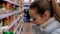 Closeup blond woman chooses pastry at shelf in supermarket
