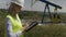 Closeup of blonde attractive engineer woman supervising oil pumping near a unit using digital tablet -