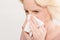 Closeup of Blonde Lady Pressing Tissue On Nose Copy Space