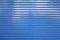 closeup blue metal roller shutter door, horizontal lines abstract background