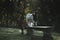 Closeup of a Boer goat standing on the stone bench and a sunlight flooding, trees blurred background