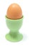 Closeup of boiled egg in green cup. White background