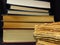 Closeup of books pile. A pile of old books is pictured against dark black background. Old books stacked in a pile.