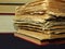 Closeup of books pile. A pile of old books is pictured against dark black background. Old books stacked in a pile.