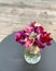 Closeup of a bouquet of sweet peas in a glass vase on the table with a blurry background