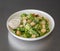 Closeup of a bowl of Caesar salad with sauce on a gray table