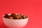 Closeup of a bowl of dried palm fruits isolated on a red background