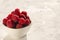 Closeup of bowl of fresh and ripe rasberries on the white surface