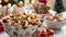 A closeup of a bowl of mixed nuts decorated with festive ribbons and p on a table filled with other party snacks