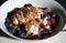 Closeup of a bowl of muesli with a spoon picking up a portion with blueberries and raspberries