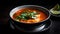 Closeup of a bowl of tomato soup with basil leaves and double cream