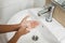 Closeup of a boy scrubbing soapy hand against washbasin