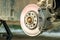 Closeup of braking disc of the vehicle with brake caliper for repair in process of new tire replacement. Car brake repairing in