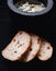 Closeup of bread slices and a black bowl of creamy spice soup on the dark background