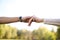 Closeup of a bride and groom holding hands on nature background with copy space