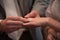 Closeup of bride putting a wedding ring onto the groom& x27;s finger. Couple exchanging wedding rings.