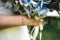 Closeup of bride`s hand holding wedding bouquet. Woman wearing golden wrist chain with connected two big rings for