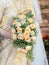 Closeup of a bride in traditional dress holding a bouquet of cream roses