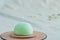 Closeup on a bright green matcha mochi on a wooden plate on a light beige fabric