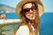 Closeup bright portrait joyful woman tourist in straw hat and sunglasses looking to camera wiht smile.