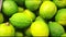Closeup of bright whole green limes on the counter of a greengrocery, 4K video, slow motion, organic fruit background.