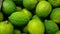 Closeup of bright whole green limes on the counter of a greengrocery, 4K video, slow motion, organic fruit background.