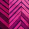 A closeup of a brightly painted magenta wall with vivid stripes zigzagging across the surface. Trendy color of 2023 Viva