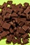 Closeup of broken, crushed dark chocolate bars stack isolated over green background