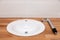 Closeup brown teak wooden empty tabletop with white round ceramic sink and tall silver water faucet. Concept repair