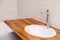 Closeup brown teak wooden empty tabletop with white round ceramic sink and tall silver water faucet. Concept repair, bathroom