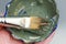 Closeup brush and green clay facial mask in bowl