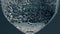 Closeup bubbles rising glass surface at dark background. Fresh pure beverage in