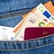 Closeup of a bunch of Euro banknotes contactless credit card and EU passport peeking out of blue jeans back pocket
