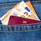 Closeup of a bunch of Euro banknotes and EU passport peeking out of blue jeans back pocket