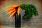 Closeup of a bunch of fresh carrots on a black bottle on the grungy gray background