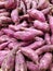 Closeup of a bunch of red sweet potatoes on a supermarket gondola.