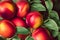 Closeup of bunch of ripe nectarine peaches with green leaves