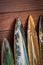 Closeup of a bunch of surfboards leaning against a wooden wall