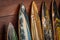 Closeup of a bunch of surfboards leaning against a wooden wall