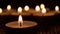 Closeup of a burning candle in the dark with  blurred candles in the background
