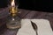 Closeup of a burning old antique hurricane oil lamp with quill pen and paper on wooden table