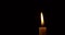 Closeup burning single candle flame isolated on black background