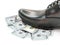 Closeup of businessman black leather shoe stepping on pile of money