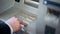 Closeup of businessman entering his pin code on keyboard of ATM, banking service