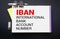 Closeup on businessman holding a card with IBAN INTERNATIONAL BANK ACCOUNT NUMBER message, business concept image