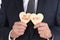 Closeup of a businessman holding two heart shaped cookies with Be Mine and XOXO written in icing. Man is unrecognizable